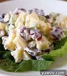 A serving of Waldorf salad on lettuce on a white plate.