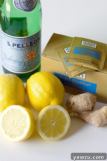 Ingredients for ginger tea lemonade including sparkling water, lemons, fresh ginger, and tea bags.