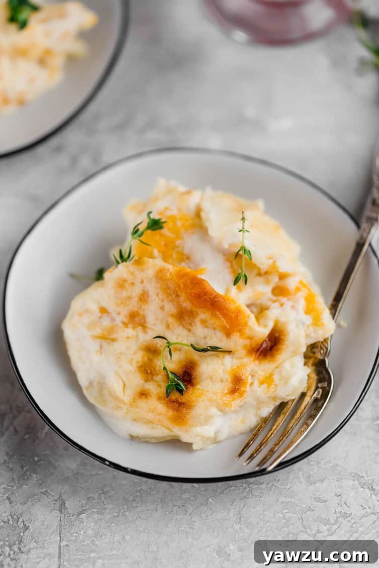 Small white bowl holding a serving of scalloped potatoes and a fork