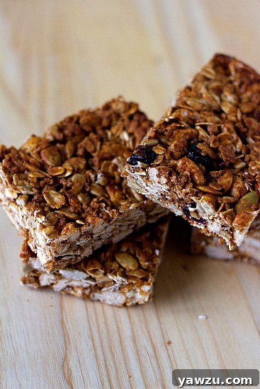 A beautifully arranged stack of homemade golden-brown granola bars on a rustic wooden surface, showcasing their delicious and wholesome appeal.