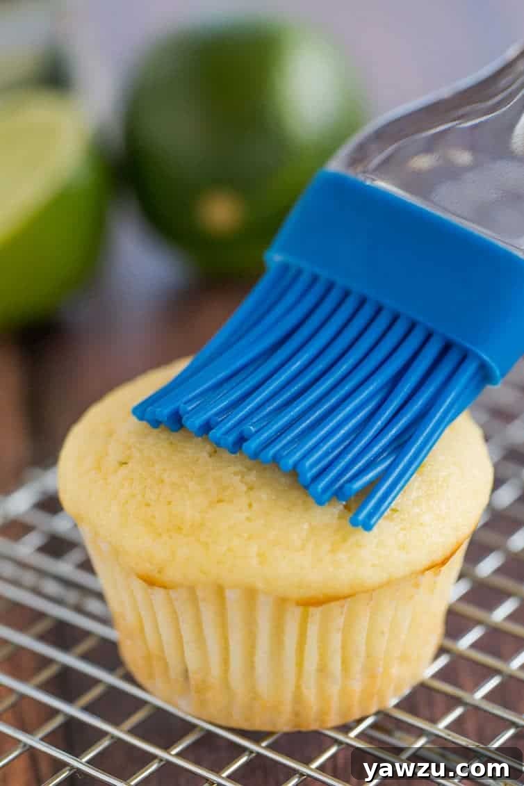 Margarita cupcakes prep: A vanilla cupcake is having tequila brushed on top with a pastry brush.