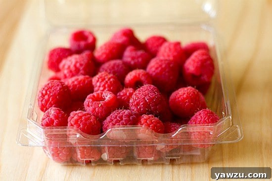 A carton filled with freshly picked, bright red raspberries, ready for baking.
