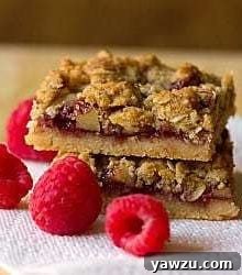 Stack of 2 raspberry streusel bars on a paper towel on a wood surface.