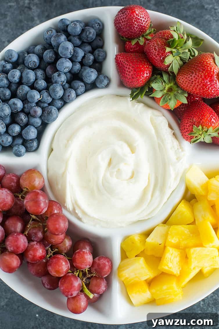A platter of fruit dip with blueberries, strawberries, grapes and pineapple.