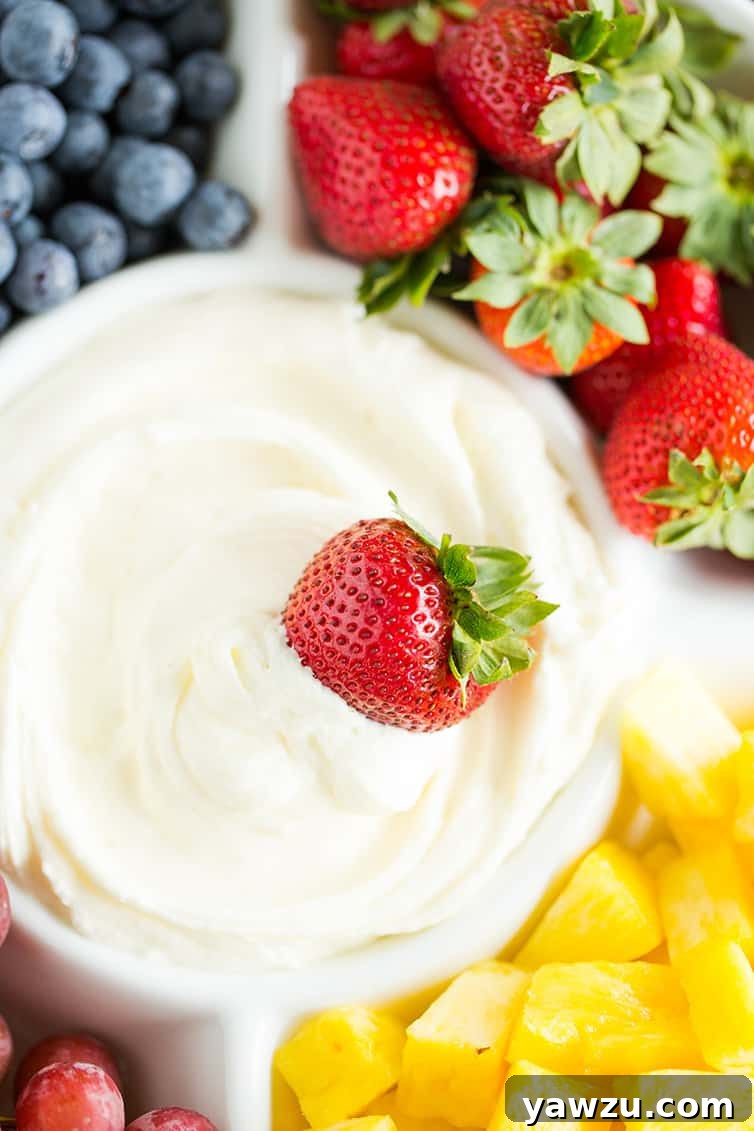 A strawberry being dipped into fruit dip.