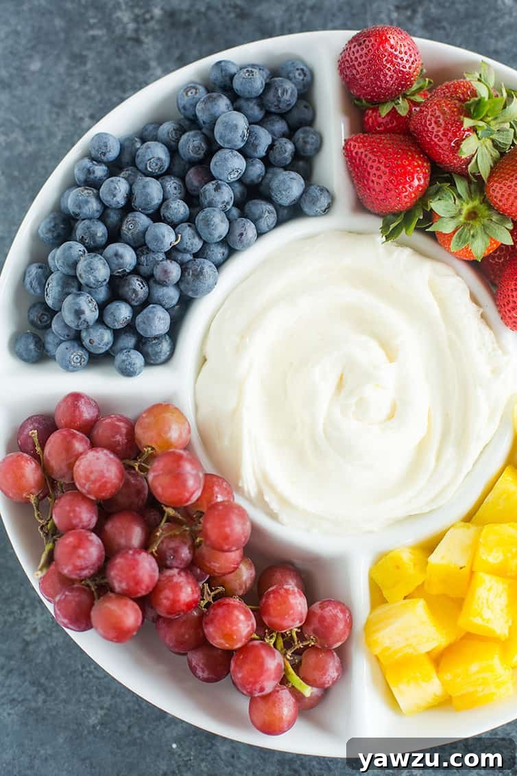A platter of blueberries, grapes, strawberries and pineapple with fruit dip.