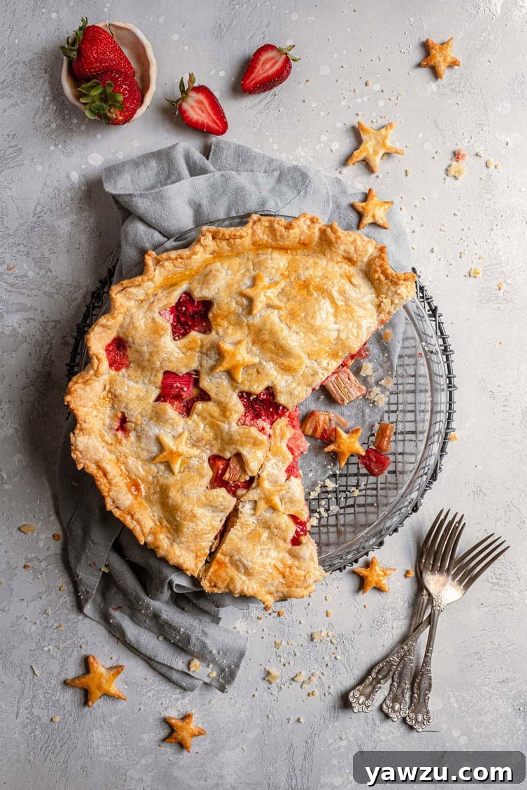 Overhead photo of strawberry rhubarb pie with two slices missing.