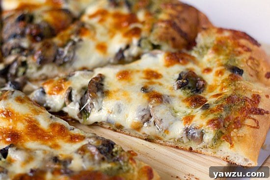 Delicious slices of portobello pesto pizza on a rustic wood cutting board, ready to be enjoyed.