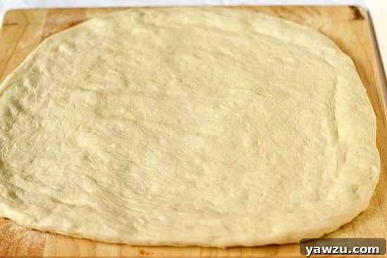 Pizza dough perfectly rolled out and shaped on a wood cutting board, ready for toppings.