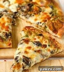 Slices of portobello pesto pizza on a wood cutting board.