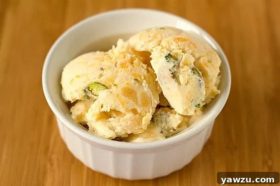 Scoops of dried apricot pistachio ice cream in a white bowl.