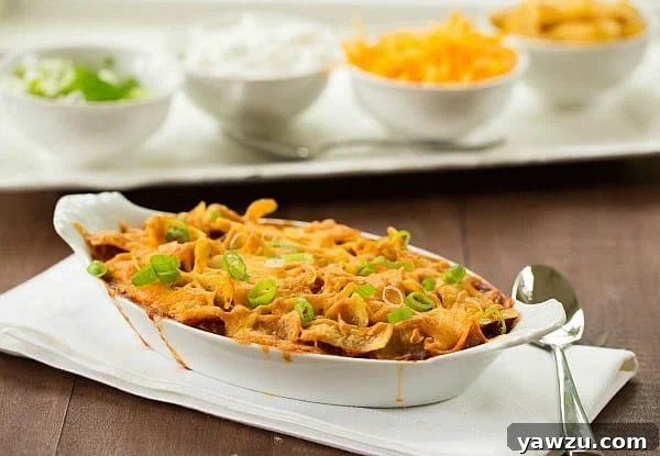 Hearty Frito Pie topped with chili, cheese, and fresh garnishes