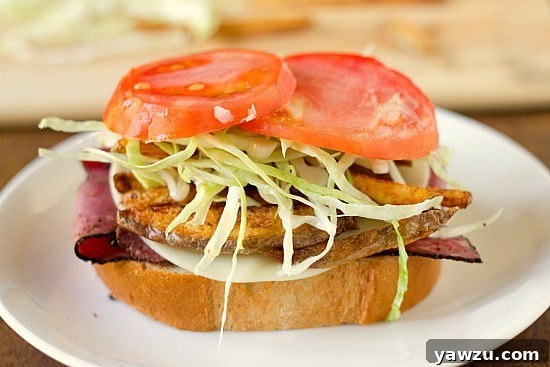 Two fresh slices of ripe red tomato placed on top of the coleslaw, adding a final touch of color and freshness to the Primanti Bros. sandwich.