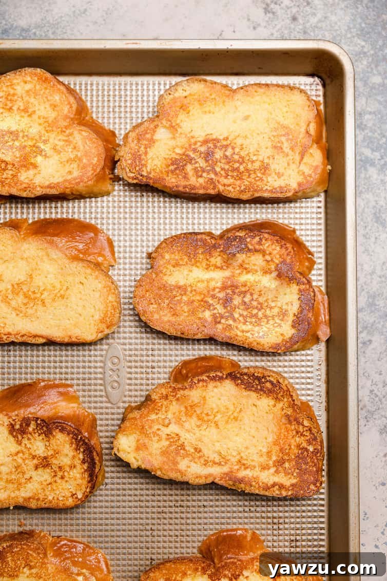 Freshly cooked Challah French toast slices arranged on a baking pan, golden brown and perfectly ready.