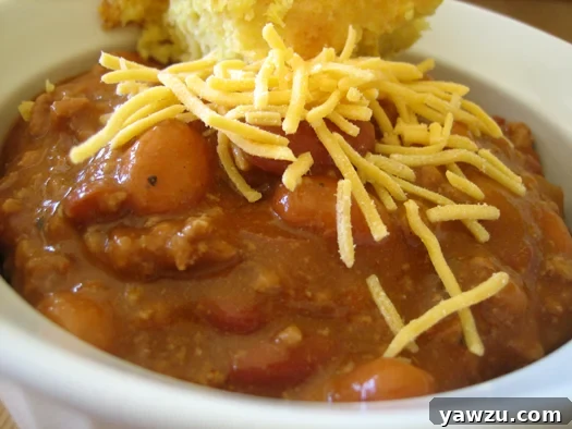Close up image of chili in a white bowl topped with shredded cheese.