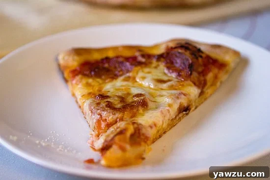 A slice of pepperoni pizza being pulled from the main pie
