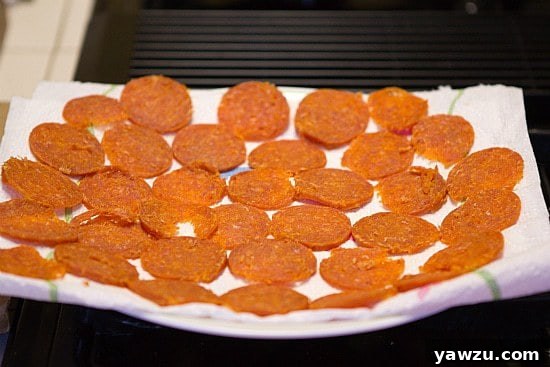 Pepperoni slices arranged on a paper towel-lined plate, ready for de-greasing