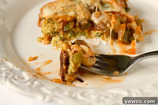 A slice of Garden Zucchini Pizza Casserole on a white plate, ready to be enjoyed.