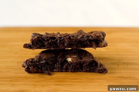 A close-up shot of a warm Triple Chocolate Oreo Chunk Cookie on a white plate, showcasing its soft, chewy center and melted chocolate pieces.