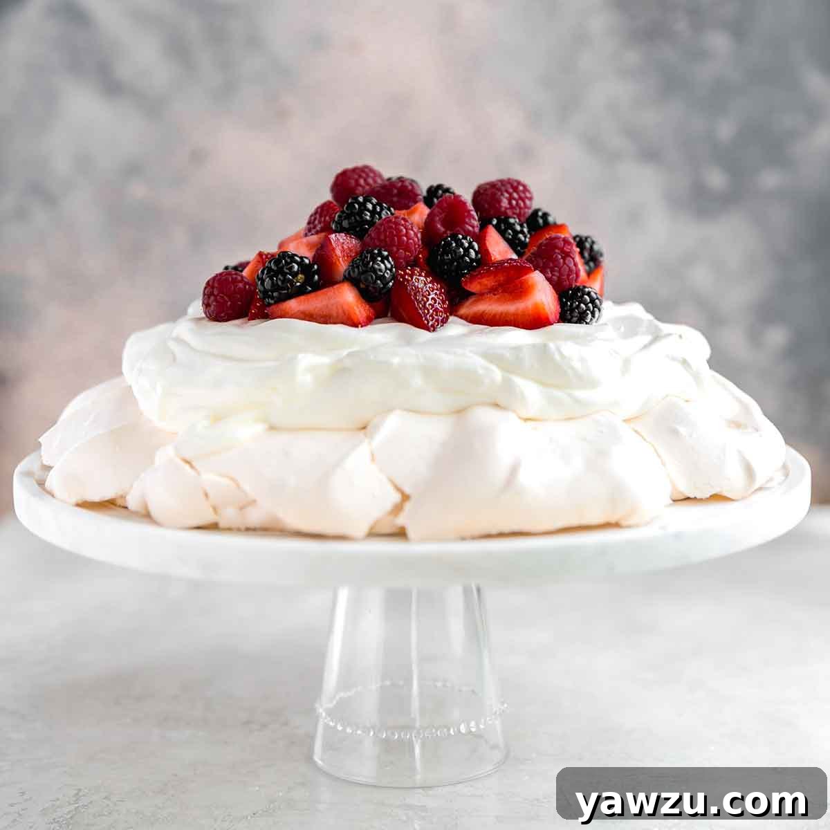 Large pavlova on a serving platter topped with whipped cream and fresh berries, showcasing its elegant and inviting presentation.