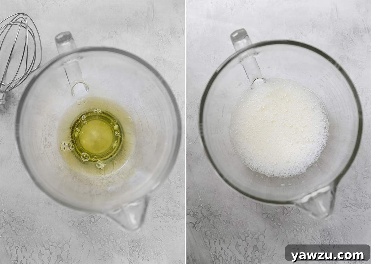 Egg whites in a glass mixing bowl being whipped to frothy peaks, illustrating the initial stage of meringue preparation.