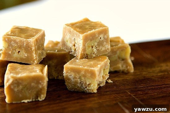 Rich, homemade maple-walnut fudge squares on a rustic wooden board, perfect for fall
