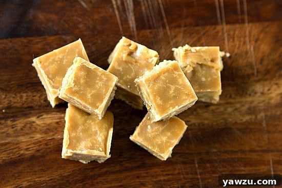 A close-up of a square of maple-walnut fudge, showcasing its creamy texture and visible walnut pieces.