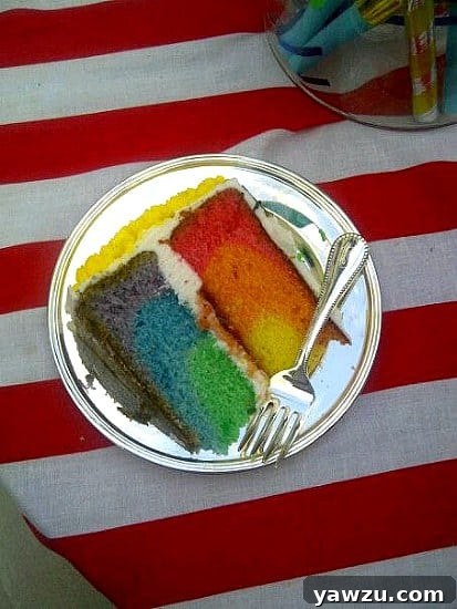 Sliced rainbow cake revealing six distinct colorful layers: red, orange, yellow, green, blue, and purple