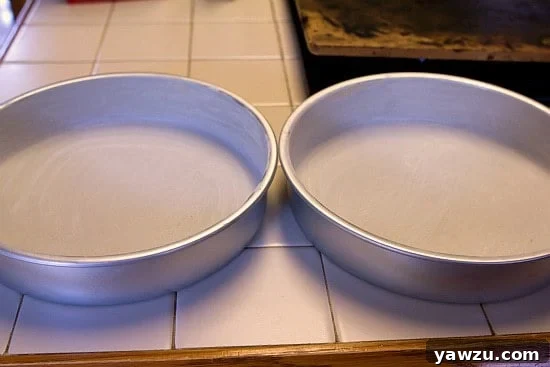 Close-up of three greased and floured cake pans, ready for batter