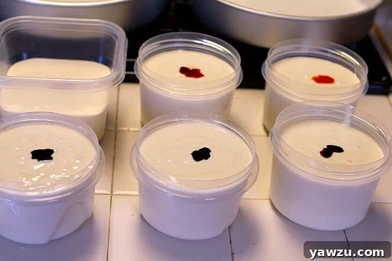 A bowl of white cake batter being stirred with yellow food coloring