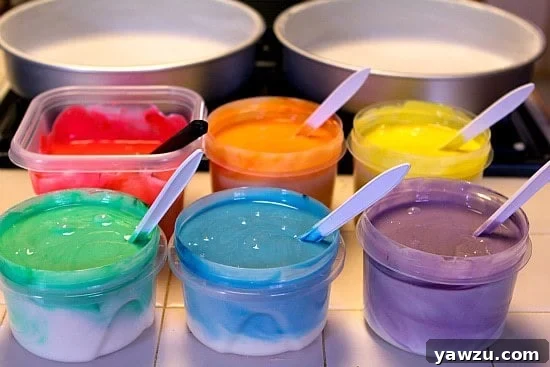 Six bowls of cake batter, each dyed a different vibrant rainbow color