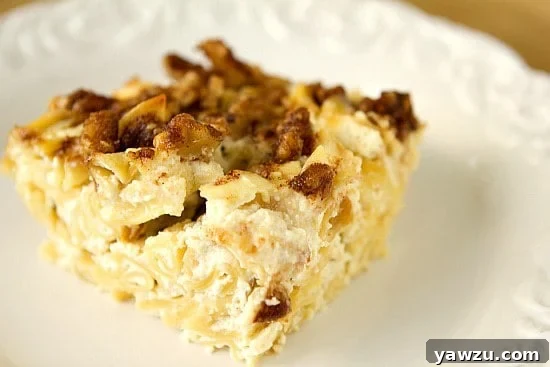 An individual portion of Noodle Kugel garnished with a small green leaf, presented on a white plate.