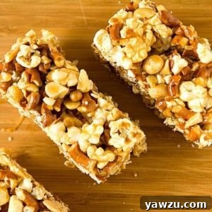 Overhead image of salted caramel popcorn, pretzel, and peanut bars on a wood board.