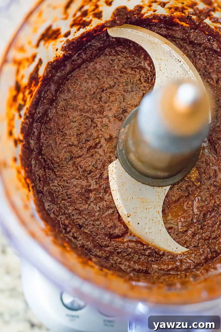 Smooth and rich homemade chili paste, ready to be incorporated into the chili, displayed in a food processor bowl.
