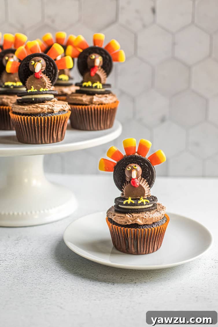 Turkey cupcake on white plate with others on cake pedastal behind.