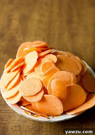 Close-up of thinly sliced sweet potatoes, ready for layering in a gratin dish.