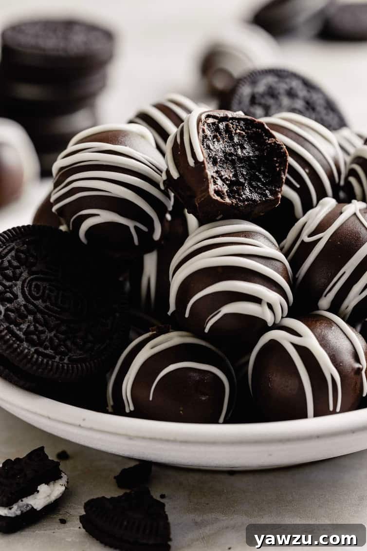 A pile of Oreo truffles on a plate with one bitten into.