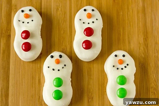 Adorable Nutter Butter Snowmen decorated with white chocolate, M&Ms, and Tic Tac noses, perfect for holiday celebrations.