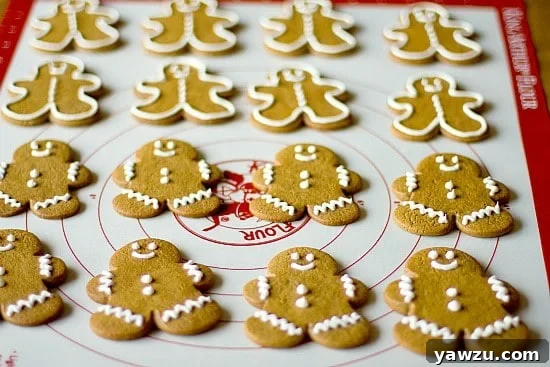 A selection of festive gingerbread cookies, some decorated and some plain, cooling on a metal wire rack.