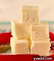 Squares of eggnog fudge stacked on a plate.