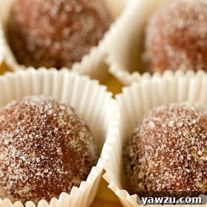 Individual chocolate bourbon balls placed in white candy wrappers.