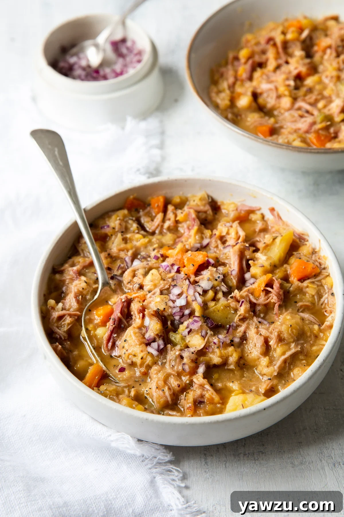Two bowls of Ham and Split Pea Soup garnished with red onion and balsamic vinegar