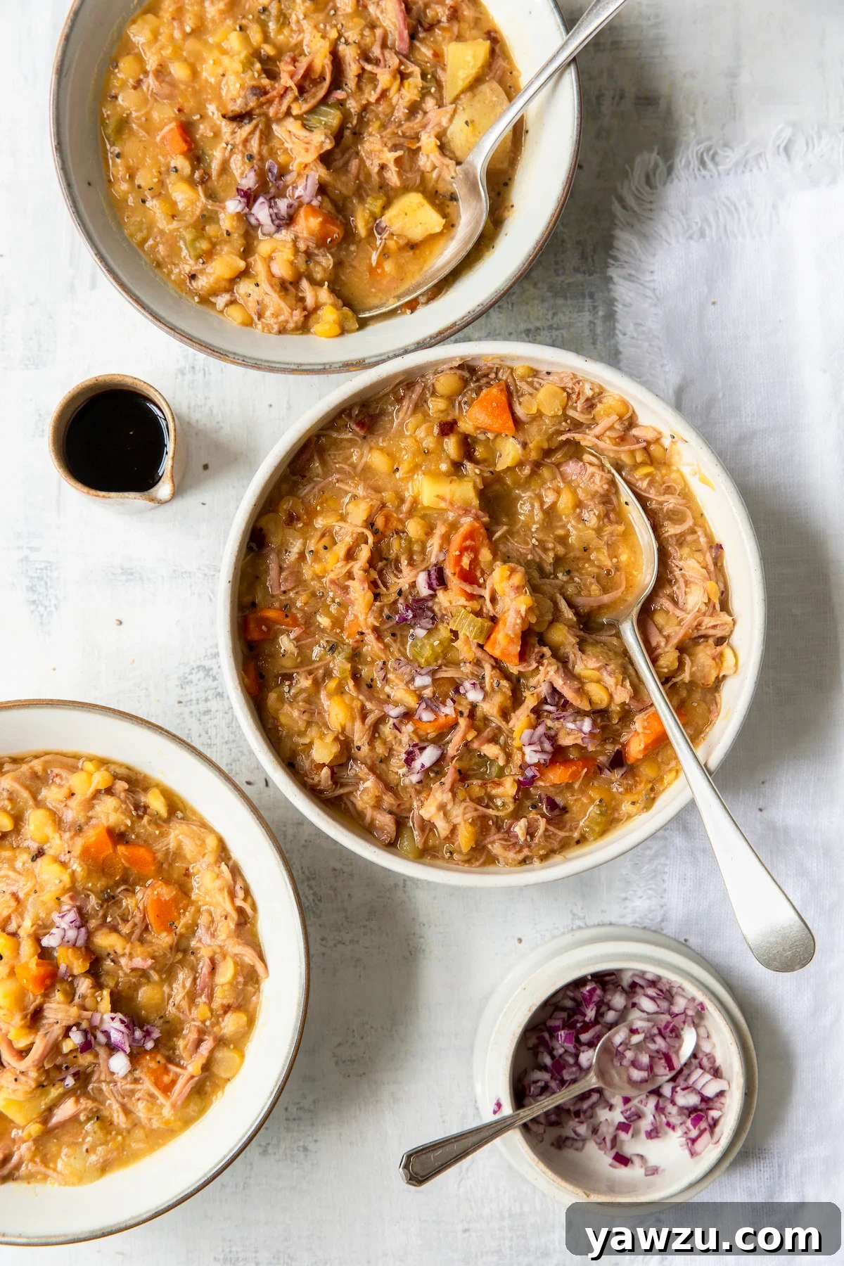 Three bowls of Ham and Split Pea Soup with small bowls of chopped red onions and balsamic vinegar