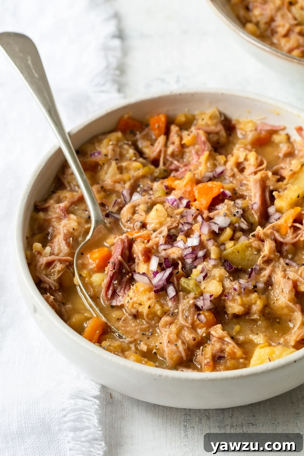 A single bowl of Ham and Split Pea Soup with a spoon resting in it