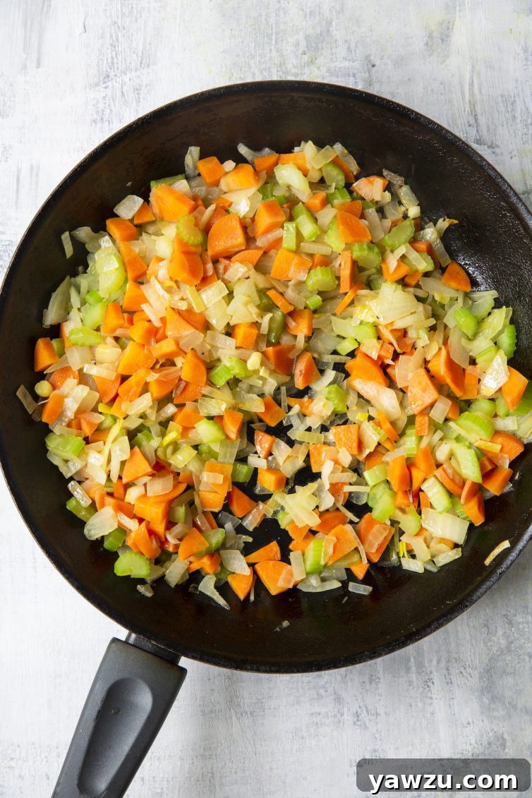 Diced onions, celery, and carrots sautéing in a skillet