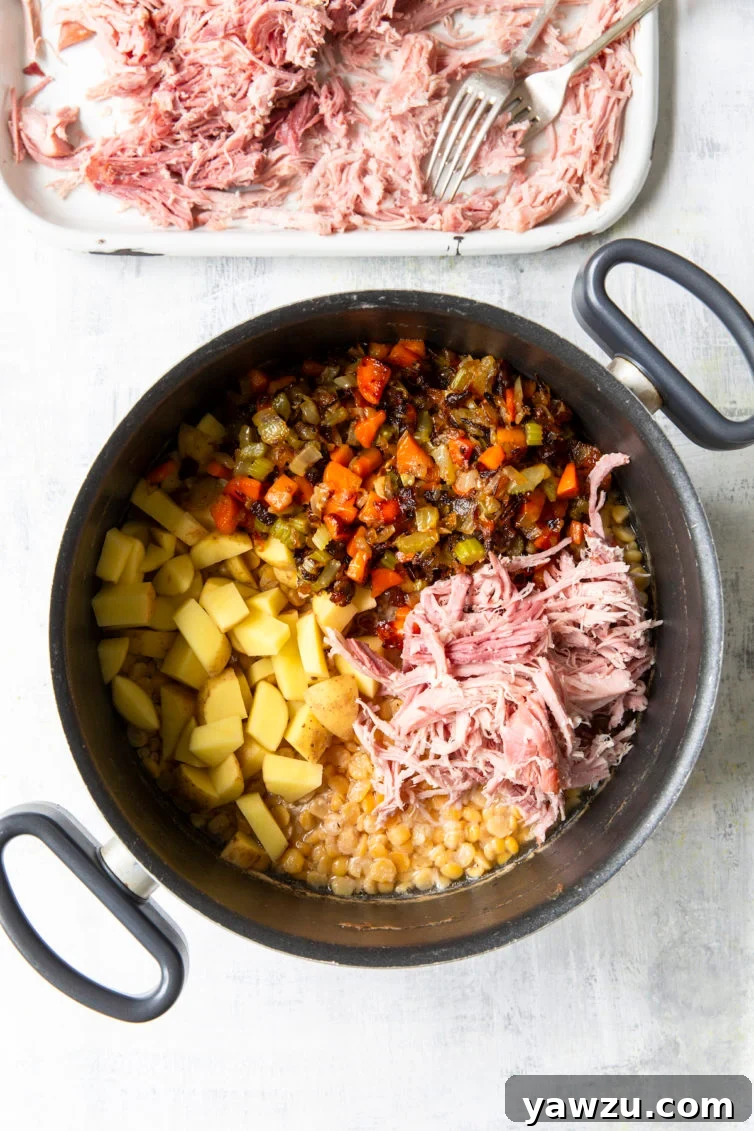 Soup ingredients in a Dutch oven with shredded ham on a platter