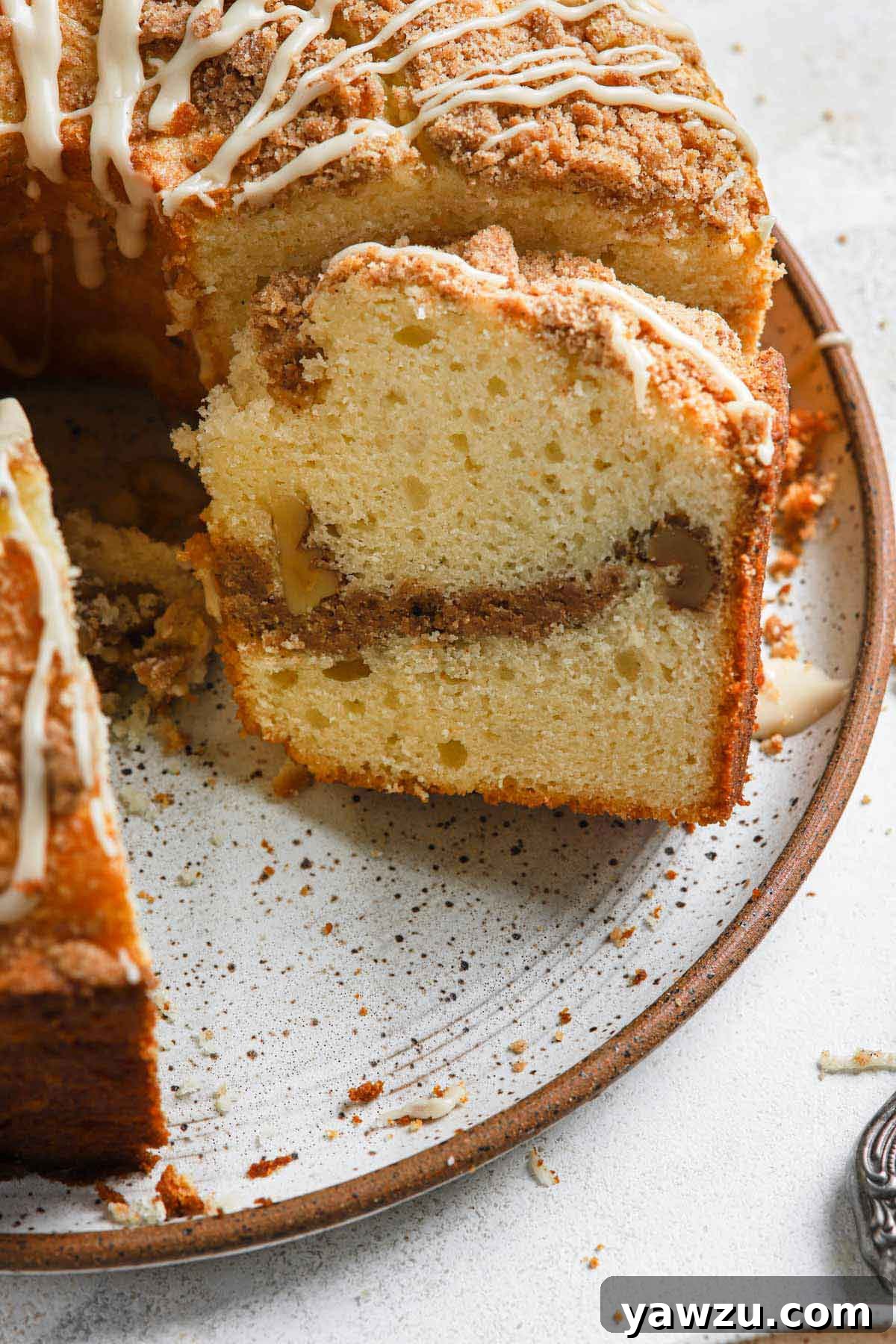 Close up photo of slice of sour cream coffee cake leaning up against the remainder of the uncut cake.