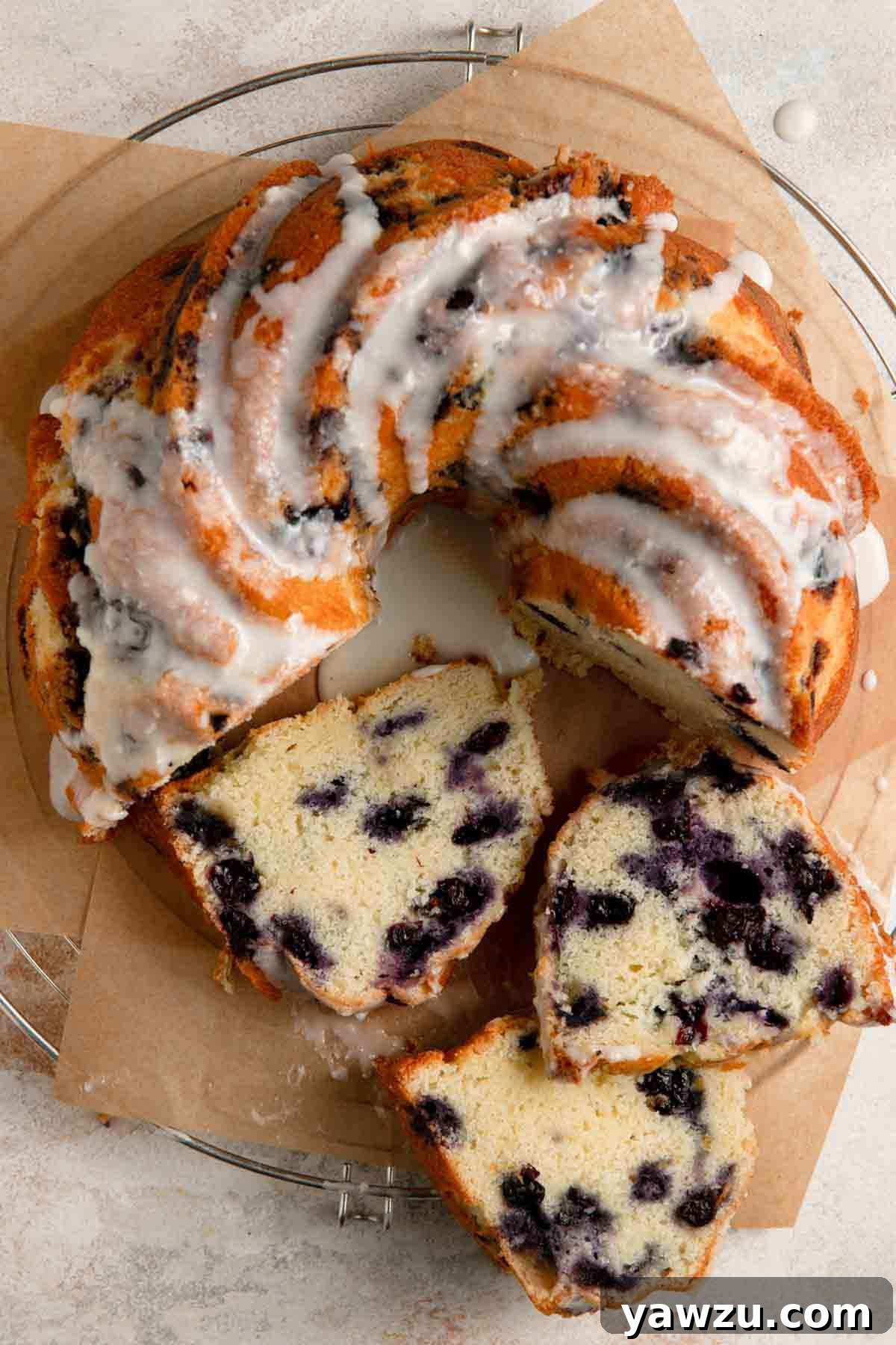 Overhead photo of three slices of lemon blueberry cake on their side in front of whole cake.