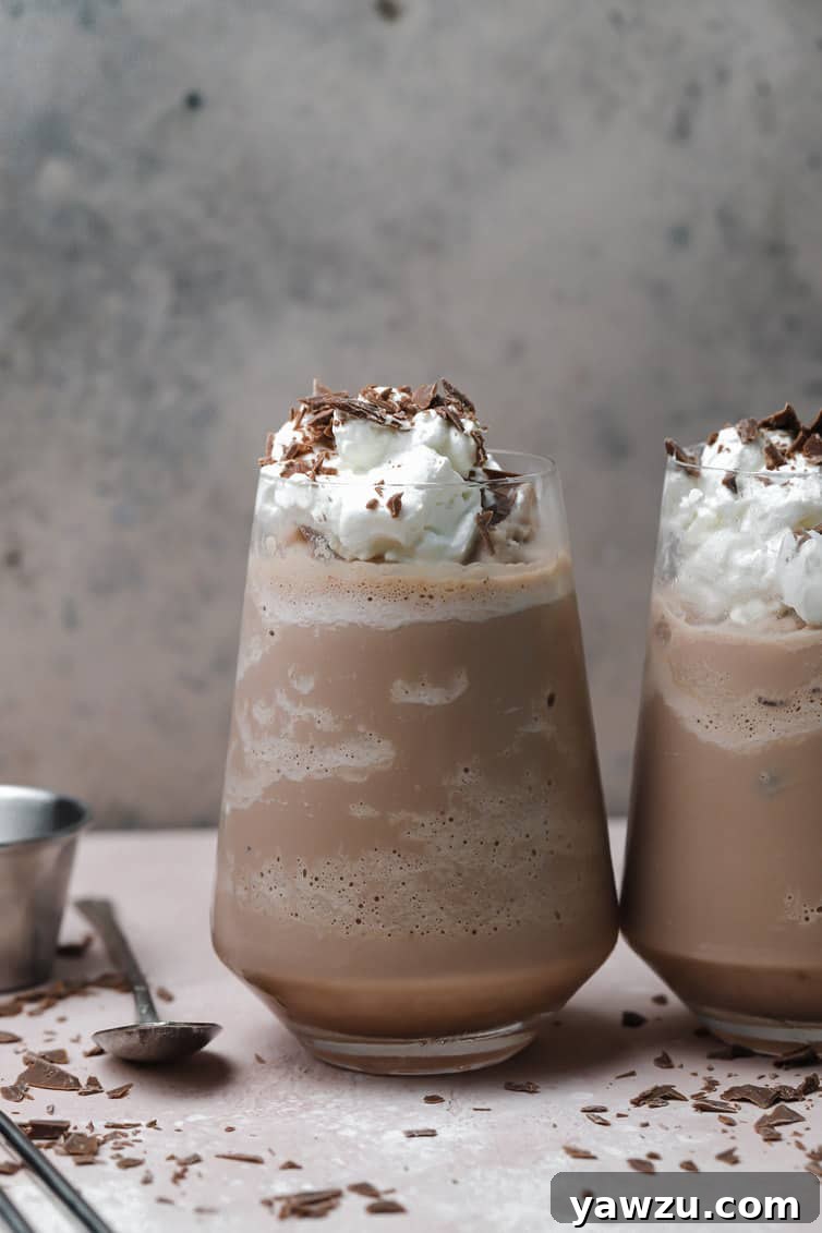 Two glasses of frozen hot chocolate topped with whipped cream and chocolate shavings.