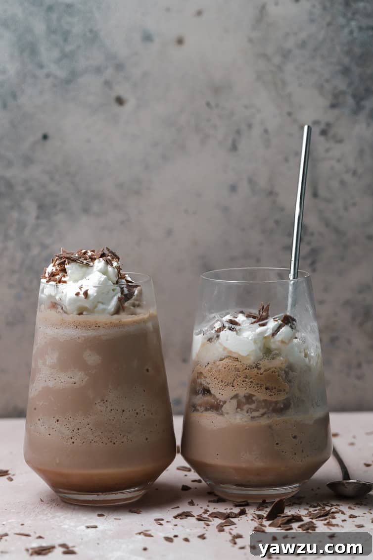 Two glasses of frozen hot chocolate, one half drank with a spoon in the glass.